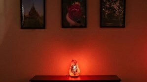 Una habitación con una mesa consola de madera, tres cuadros en la pared y una luz ambiental roja.