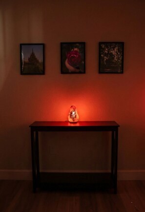 Una habitación con una mesa consola de madera, tres cuadros en la pared y una luz ambiental roja.