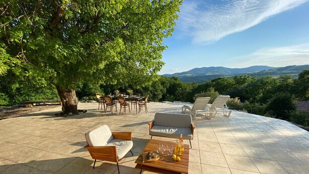 Eine Terrasse im Freien mit Tisch, Stühlen und Blick auf die Landschaft.