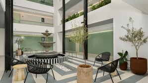 A modern lobby with a central fountain, tiered seating, and potted plants. - Sage Sea Point 1 Bed Ocean View (Cape Town)
