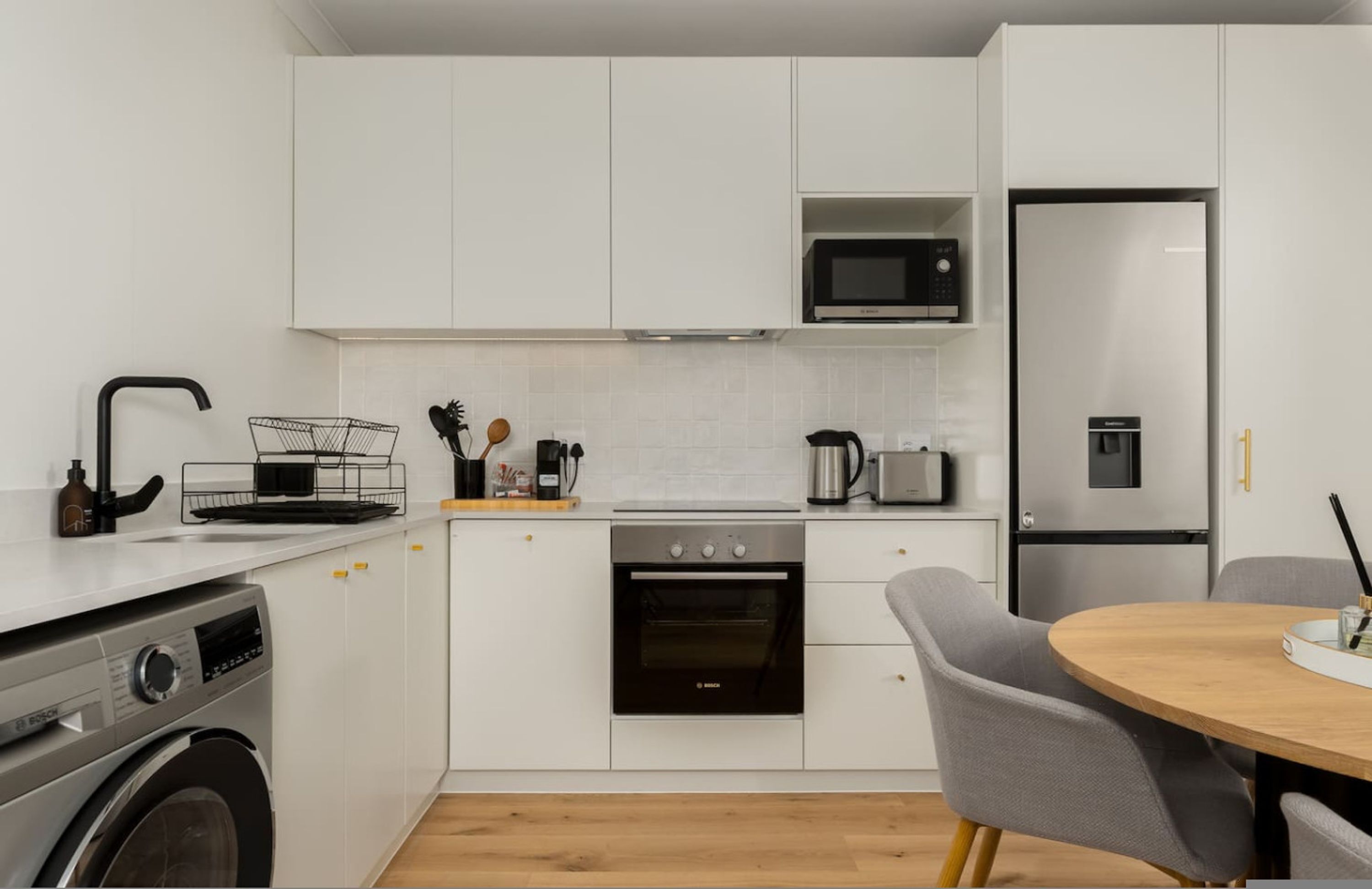 A compact kitchen with a Bosch oven, a microwave, a refrigerator, and a sink.