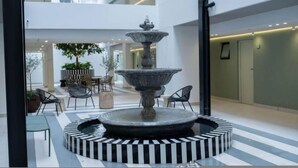 En atriumgård i flera våningar med en central fontän, sittområden och inomhusväxter.