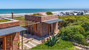 A coastal building with a brick exterior, a small dome structure, and a view of the ocean. - Yzerfontein 3 Bed House With Pool Sea Views (Yzerfontein)