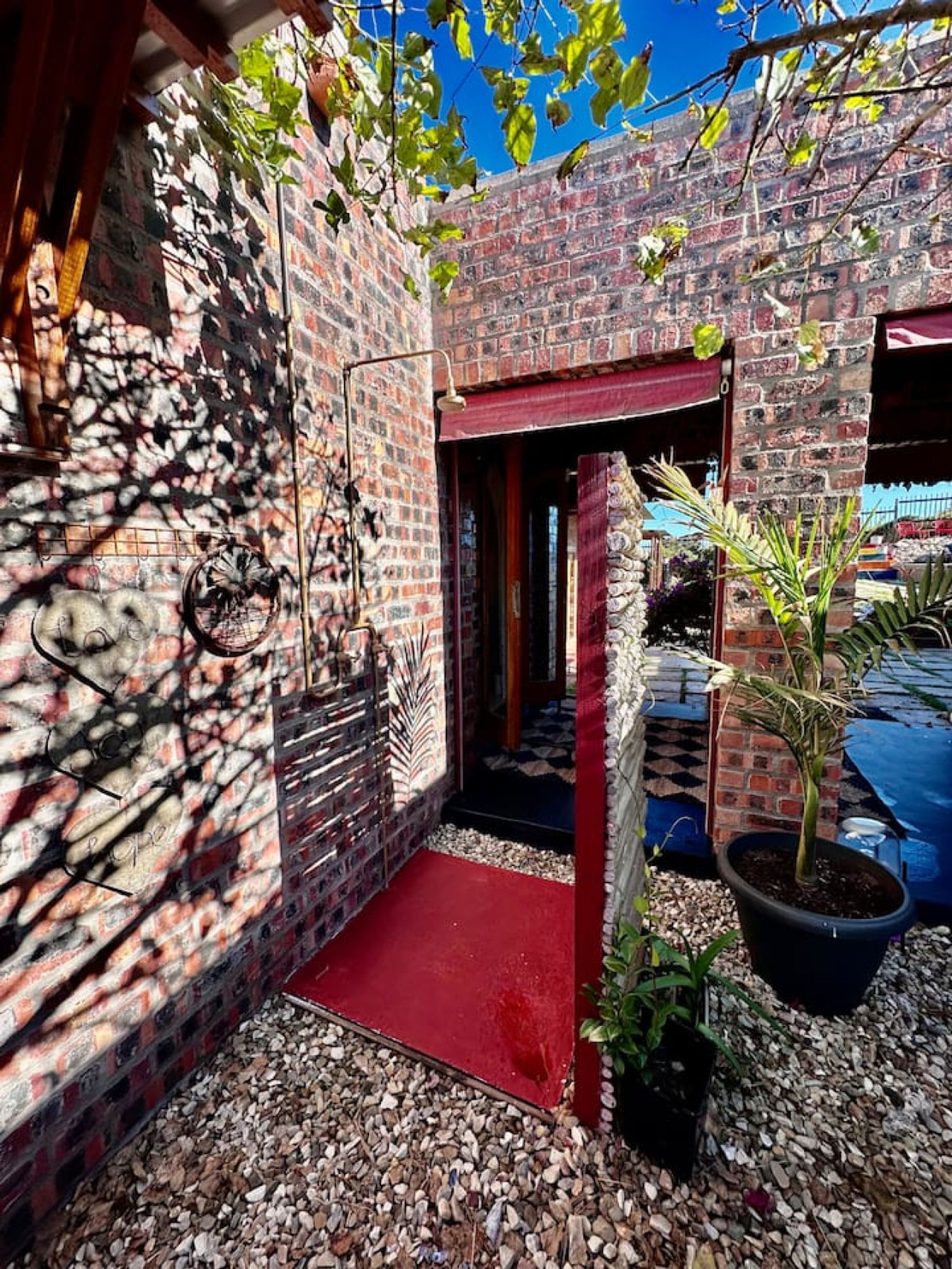 A brick courtyard with a red carpet, potted plants, and a hanging light fixture.