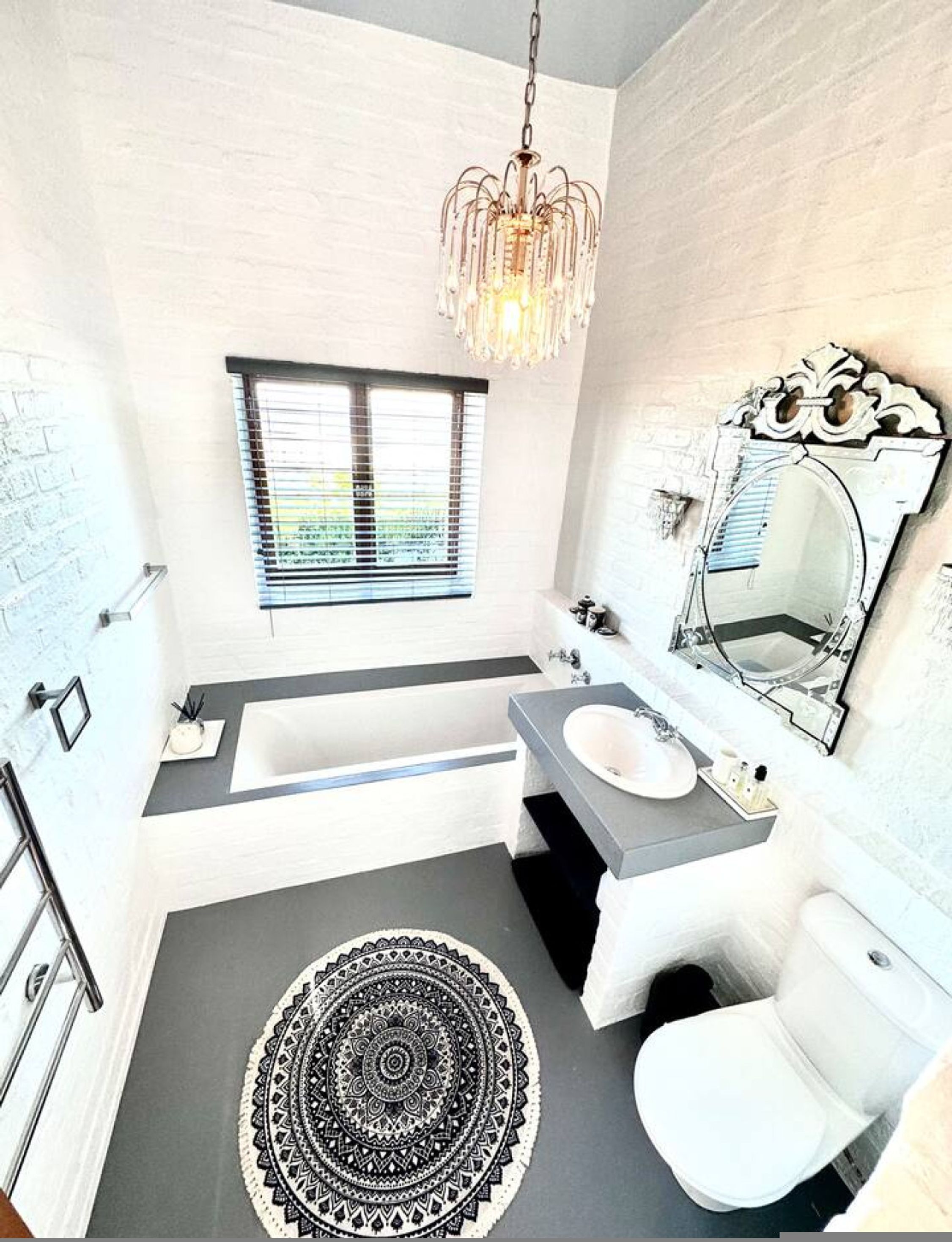 A modern bathroom with a bathtub, sink, toilet, and a large mirror.