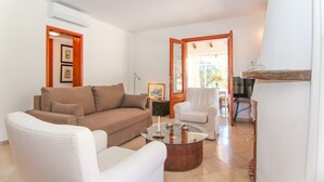 A living room with a sofa, armchairs, a coffee table, and a TV. - Finca Ca l'Hereu Petit 282 by Mallorca Charme (Cala Sant Vicenç)