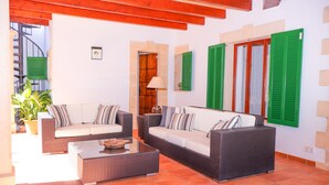 A room with two wicker sofas, a coffee table, and green shutters on the windows. - Finca Ca l'Hereu Petit 282 by Mallorca Charme (Cala Sant Vicenç)