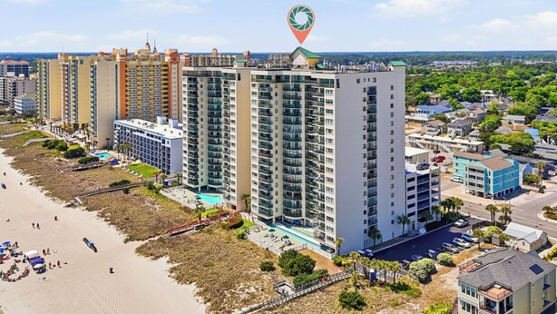 A high-rise hotel with multiple floors, a swimming pool, and a beach area. - Ocean Front Condo- Indoor & Outdoor Pools- Lazy River + Hot Tub (North Myrtle Beach)