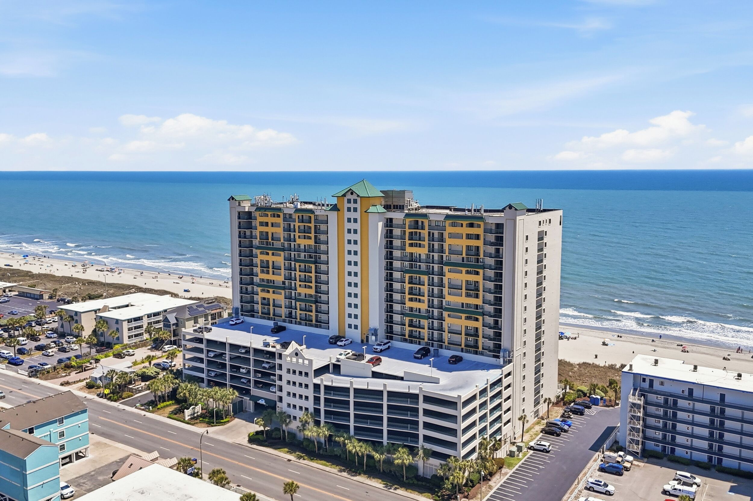 Un hôtel de grande hauteur, avec de nombreux étages, un parking sur le toit et une vue sur la plage.