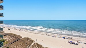 A beach with a clear sky, a sandy shore, and a few people and umbrellas. - Ocean Front Condo- Indoor & Outdoor Pools- Lazy River + Hot Tub (North Myrtle Beach)