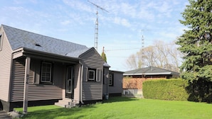 A two-story house with a sloped roof, a front porch, and a well-maintained lawn. - 3BR home w/ large yard near wineries & outlet (Niagara-on-the-Lake)