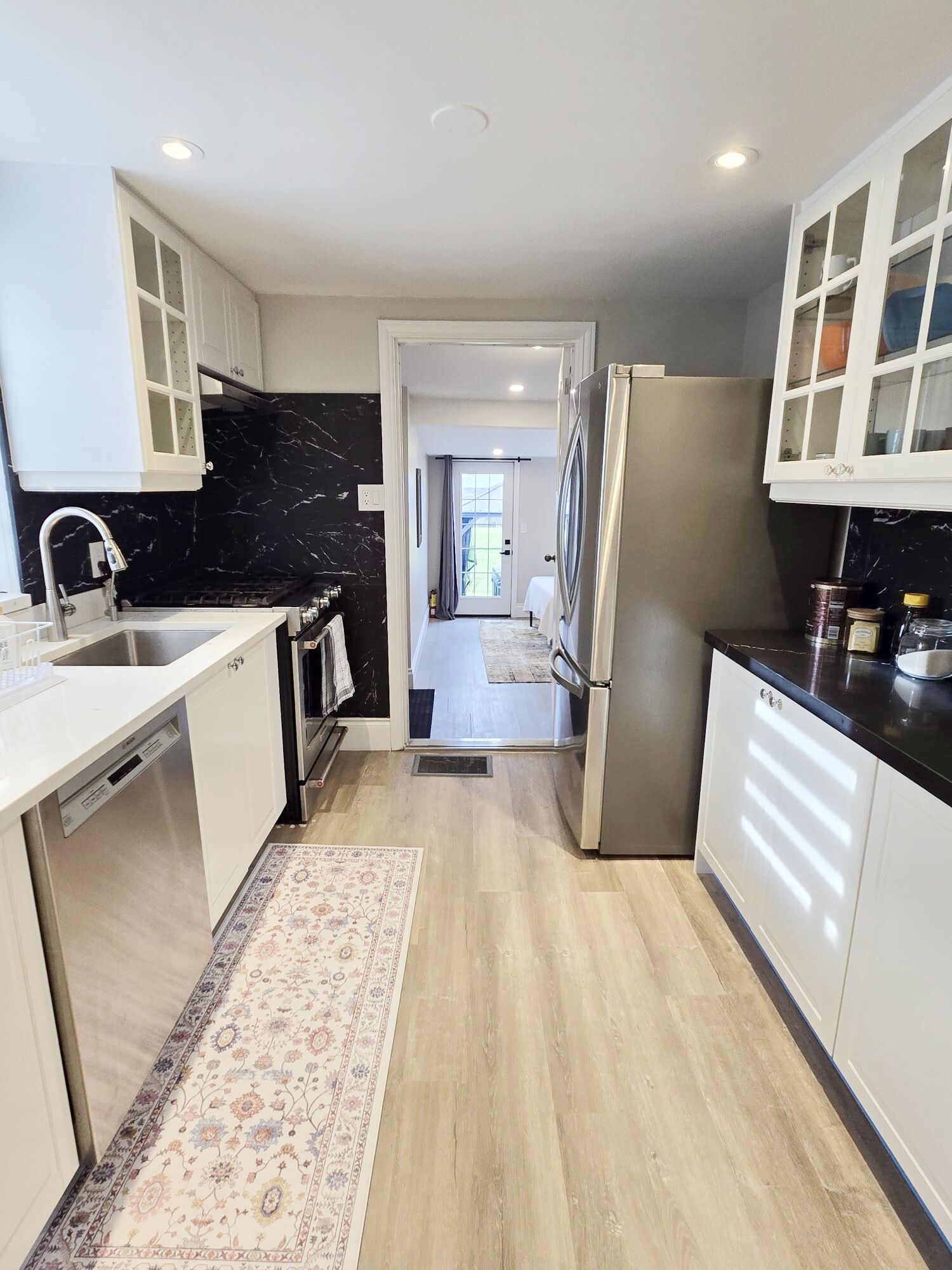 A modern kitchen with white cabinets, a marble backsplash, and a stainless steel refrigerator. - 3BR home w/ large yard near wineries & outlet (Niagara-on-the-Lake)