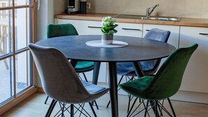 A modern kitchen with wooden cabinets, a round dining table with chairs, and a view through a glass door. - Apart Vinschgau (Val Venosta) - charming, cozy apartment with mountain view (Laudes)