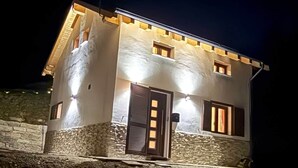 A two-story building with a stone facade, a flat roof, and a small antenna on the roof. - Chalet Valmalenco - Valtellina (Provincia di Sondrio)
