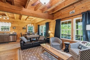 Ein Blockhaushaus-Interieur mit Küche, Wohnzimmer und großen Fenstern.