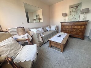 A living room with a sofa, armchair, wooden coffee table, and a dresser with a mirror. - Riviera Beauty, Sun & Sea 80 m² close to the Mediterranean 4 pers, Clim, Pkg (Cagnes-sur-Mer)