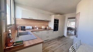 A modern kitchen with a wooden countertop, a sink, a toaster, and a stove. - Riviera Beauty, Sun & Sea 80 m² close to the Mediterranean 4 pers, Clim, Pkg (Cagnes-sur-Mer)