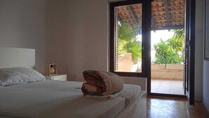 Un dormitorio con cama, mesita de noche y ventana con vistas a la vegetación.