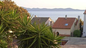 Una piscina rodeada de baldosas de piedra, con vistas a casas y una masa de agua al fondo.