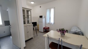 A compact kitchen with a dining area, a refrigerator, a microwave, and a cabinet. - Comfortable Property Seafront in Caorle (Caorle)