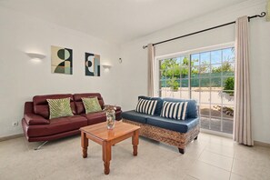 A living room with a red leather sofa, a blue sofa, a wooden coffee table, and abstract wall art.