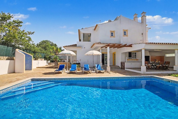 A two-story house with a swimming pool, outdoor seating, and a patio area.