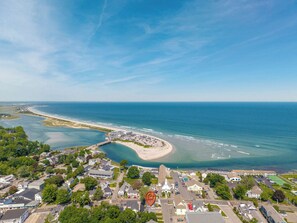 Luchtbeeld van een kustplaatsje met een strand, woonwijken en een opvallende kerk.