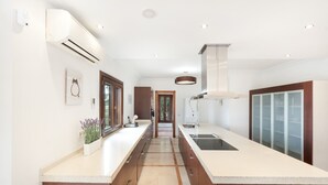 A modern kitchen with a central island, built-in appliances, and a view to the dining area. - Villa 'Mirador' con piscina compartida, Wi-Fi y aire acondicionado (Coín)