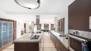 A modern kitchen with a central island, stainless steel appliances, and a view to the dining area. - Villa 'Mirador' con piscina compartida, Wi-Fi y aire acondicionado (Coín)