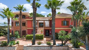 A two-story building with a swimming pool, palm trees, and a stone staircase leading to the entrance. - Villa 'Mirador' con piscina compartida, Wi-Fi y aire acondicionado (Coín)