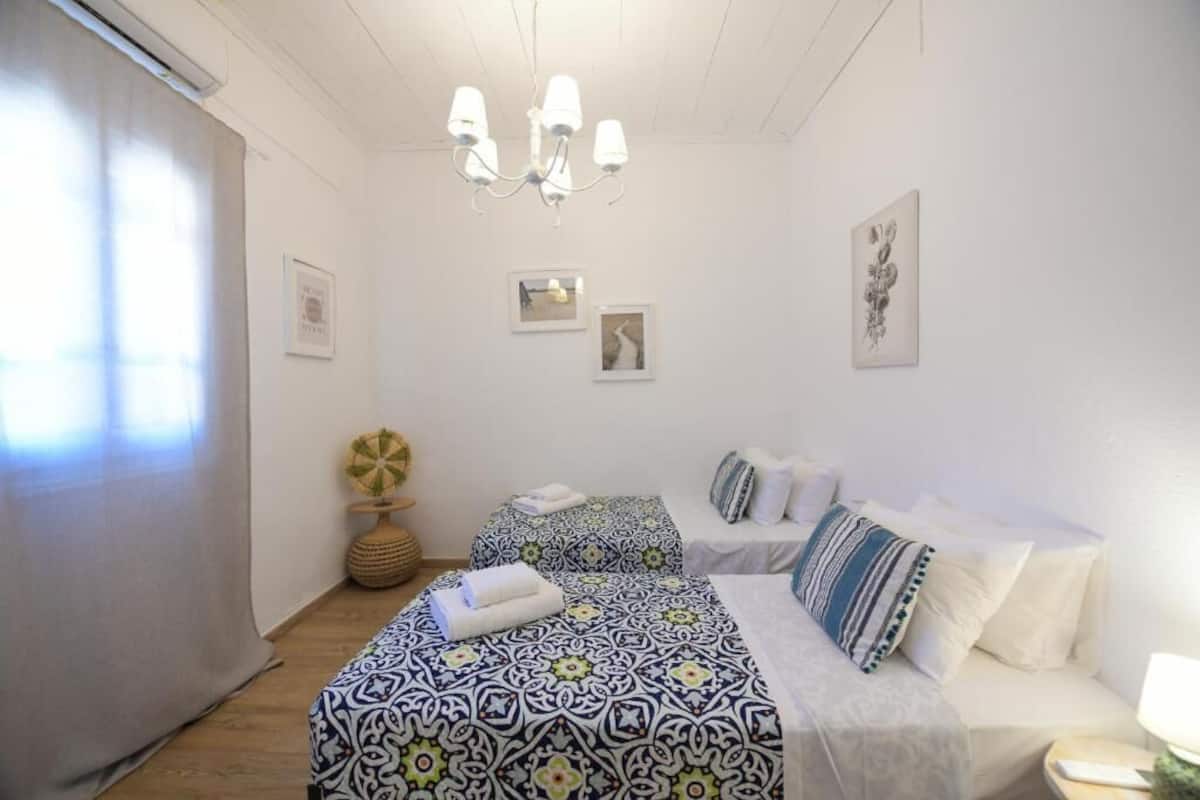 Una habitación con dos camas, una araña, cuadros enmarcados y una mesa redonda con un globo terráqueo.