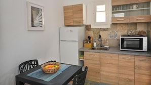 A compact kitchen with a refrigerator, microwave, and wooden cabinets. - MZ Mykonos Rock (Mykonos)