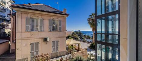 A two-story building with a balcony, a view of the sea, and a garden area.