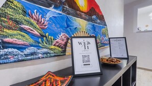 A reception desk with a framed artwork, a QR code for Wi-Fi access, and a framed certificate. - [Ospedale S. Paolo 2 min] HiperWifi • SmartTV • AC (Savona)