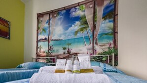 A bedroom with a tropical mural, a bed with blue bedding, and a set of toiletries on a towel. - [Ospedale S. Paolo 2 min] HiperWifi • SmartTV • AC (Savona)