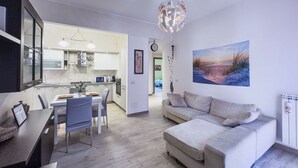 A modern living room with a sofa, dining table, and kitchen area. - [Ospedale S. Paolo 2 min] HiperWifi • SmartTV • AC (Savona)
