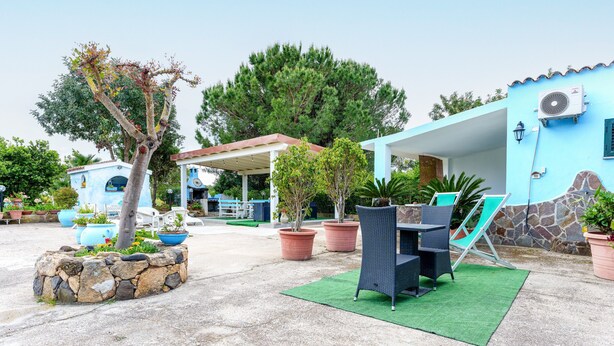 A patio area with outdoor furniture, a stone planter, and a covered seating area. - Sardinian Apartment for 6 with Private Terrace, Three Minutes’ Walk from the Beach (Orosei)