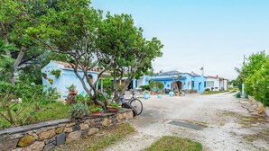 A blue building with a stone wall and potted plants. - Sardinian Apartment for 6 with Private Terrace, Three Minutes’ Walk from the Beach (Orosei)