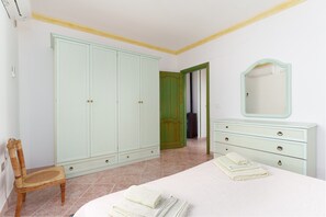 Un dormitorio con cama, cómoda, silla y armario.