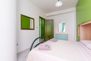 Ein Schlafzimmer mit Bett, Stuhl, Kommode und einer grünen Tür.