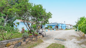 A blue building with a stone wall and potted plants. - Sardinian Apartment with Private Terrace 3 Minutes’ Walk from the Beach (Orosei)