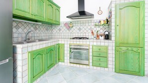 A kitchen with green cabinets, a stainless steel oven, and a black range hood. - Sardinian Apartment with Private Terrace 3 Minutes’ Walk from the Beach (Orosei)