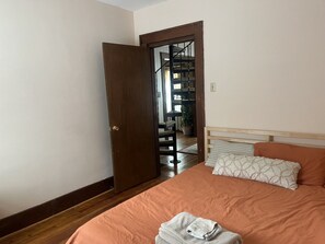 A bedroom with a bed, a wooden door, a staircase, and a potted plant. - Serene 3-bedroom house in charming Syracuse (Syracuse)