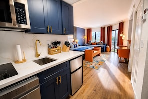 Une cuisine moderne avec des meubles de couleur bleu foncé, un four à micro-ondes en acier inoxydable et un porte-ustensiles en bois.