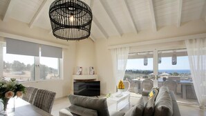 En moderne stue med sofa, fjernsyn, spisebord og en balkon med havemøbler.