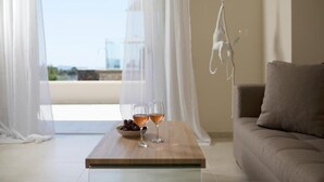 Et værelse med et træbord, to glas vin, en skål druer og udsigt gennem lette gardiner.