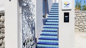 Un edificio blanco con una escalera azulada de azulejos, una reja metálica decorativa y un cartel que indica 'Palace of Santelena'.