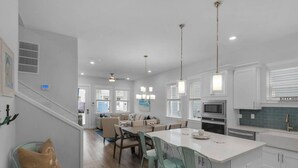 A modern kitchen with white cabinets, a central island, and pendant lighting. - Emerald Escape 30A (Santa Rosa Beach)