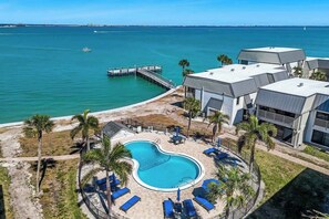 A pool area with lounge chairs, a dock, and a view of the ocean. - Sanibel Waterfront 3BR | Dock, Pool, Pickleball (Sanibel)