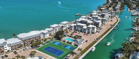A coastal hotel with multiple buildings, a tennis court, and a marina.